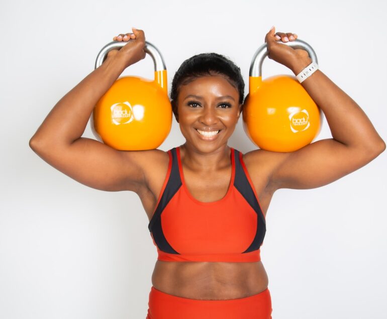 a woman holding two orange kettles over her head