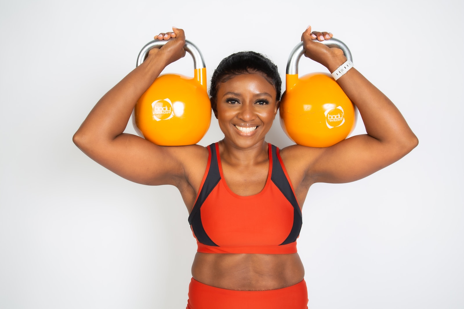 a woman holding two orange kettles over her head
